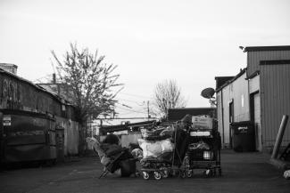 Unhoused individual with two trolleys filled to the brim sleeping in Seattle. Washington.